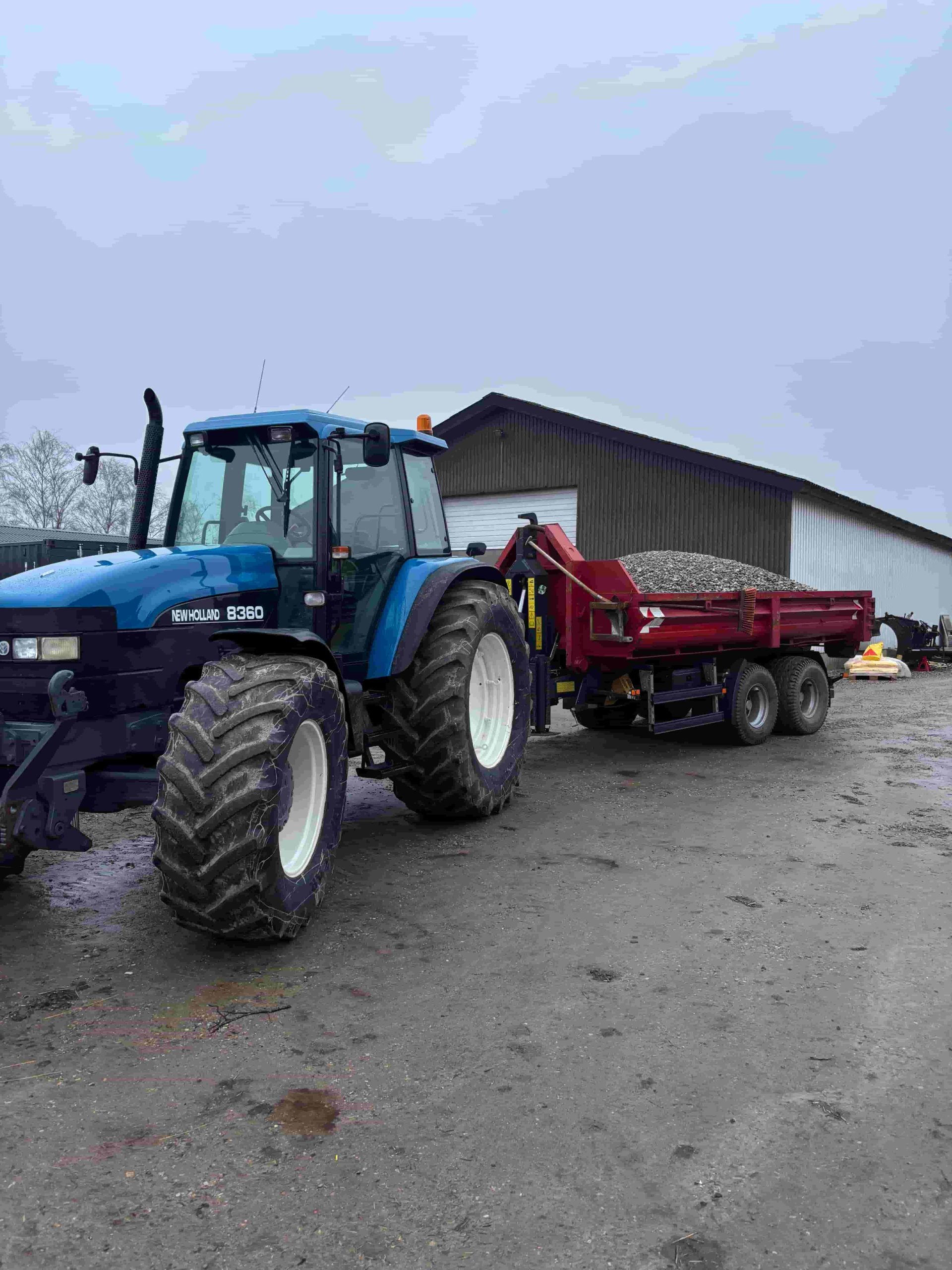 LC-Agro traktor med læsset tipvogn ved gård